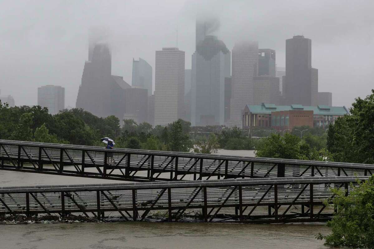 People walk over the Rosemont Pedestrian Bridge to look at a flooded Buffalo Bayou as Hurricane Harvey continues to dump rain over downtown Houston on Tuesday, Aug. 29, 2017.