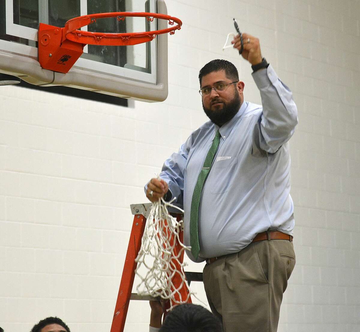 Head coach Adam Zepeda cuts down the final pieces of the net to commemorate the Whirlwinds’ District 4-2A title.