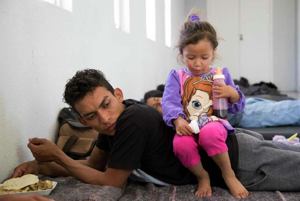 Jennifer, 2, drinks a coke from a bottle while sitting on her father Misael Acosta at the shelter her family are staying at in April 2019 in Ciudad Juárez, Mexico. They were among the first asylum seekers returned to Ciudad Juárez under the Trump administration’s policy of making migrants wait in Mexico for their U.S. court dates. On Friday, a California federal court blocked the program, though an appeal to the Supreme Court is likely.