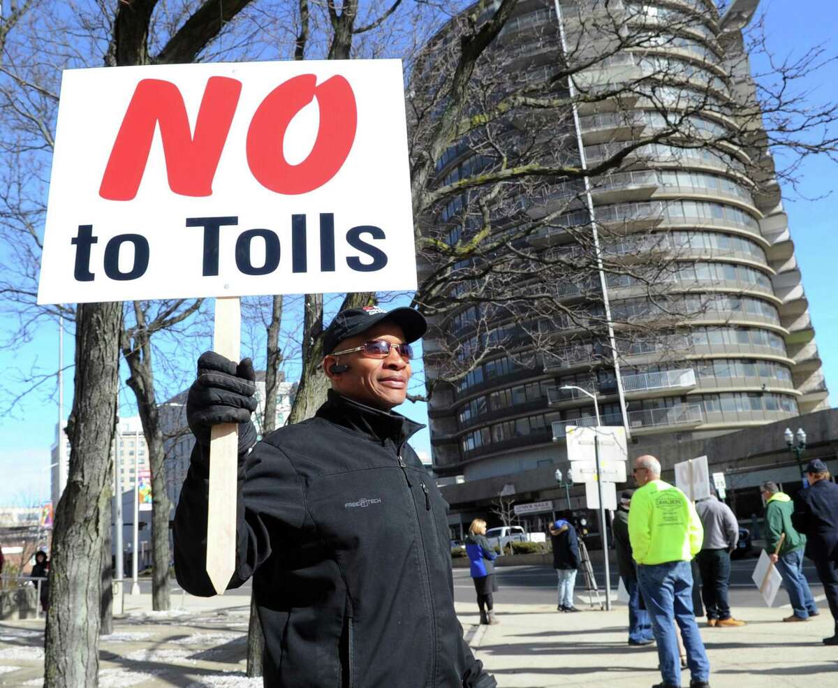 Holding a sign that reads "No to Tolls," Nate Taylor of Stamford, an owner of a small business cleaning service in Stamford since 1980, said he is against tolls and taxes "they are running us out of business and out of the state," during the protest against tolls, a new gas tax and tire tax, held in front of the Stamford Goverment Center, Stamford, Conn., Saturday, Feb. 17, 2018. Roughly 75 people attended the protest that was accompanied by a caravan of trucks circling the center honking their horns in support of the protestors. Gov. Dannel P. Malloy wants legislators to pass measures including electronic tolls, an increase in state gasoline taxes and a new tax on the sale of tires, to pay for Connecticut's transportation system that he says is facing a serious fuding crisis.