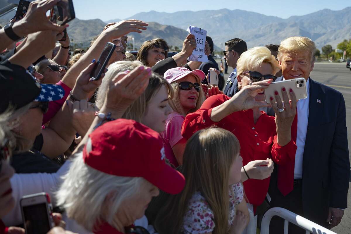 US President Donald Trump takes selfies with supporters as he arrives in Palm Springs, California, on February 19, 2020.