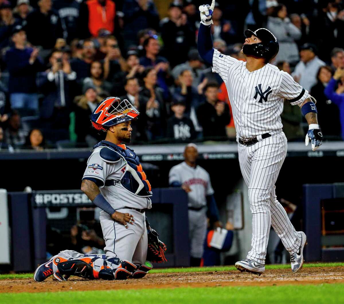 Houston Astros catcher Martin Maldonado (12) watches as New York Yankees second baseman Gleyber Torres (25) crosses home plate after hitting a solo home run during the eighth inning of Game 3 of the American League Championship Series at Yankee Stadium in New York on Tuesday, Oct. 15, 2019.