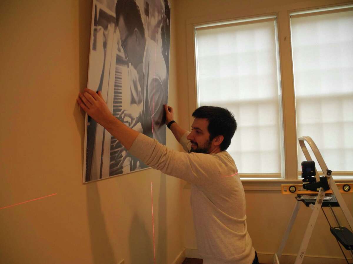 Associate Curator Nick Foster hangs a photo of Dave Brubeck for the Wilton Historical Society’s upcoming exhibition, Remembering Dave: A Brubeck Family Album, opening Feb. 21.