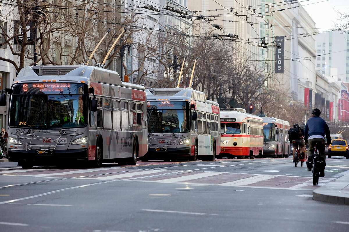 Cyclists move past a row of Muni buses and street cars lined up on Market Street in San Francisco, Calif. Wednesday, January 29, 2020. Beginning January 29, private vehicles will be banned from driving along Market Street between Steuart and 10th streets, leaving it free for cyclists, pedestrians and public transit vehicles.