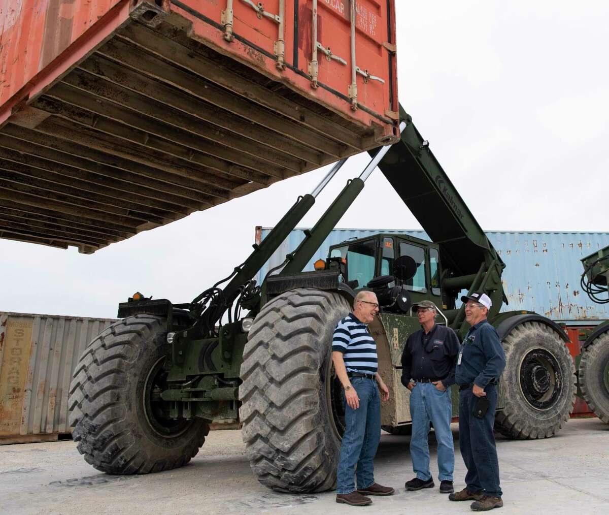 Stephen M. Speakes, left, CEO and president of the Independent Rough Terrain Center in Cibolo, speaks with Steve Stephens and George Deck by a vehicle called the Rough Terrain Container Handler, or RTCH.