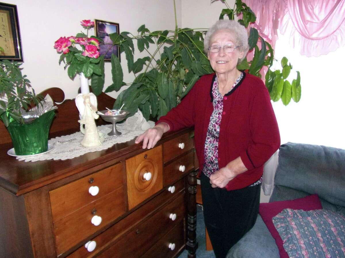 Freda Maust poses for a photo next to her century-old bureau that was made by her grandfather. (Rich Harp/For the Tribune)