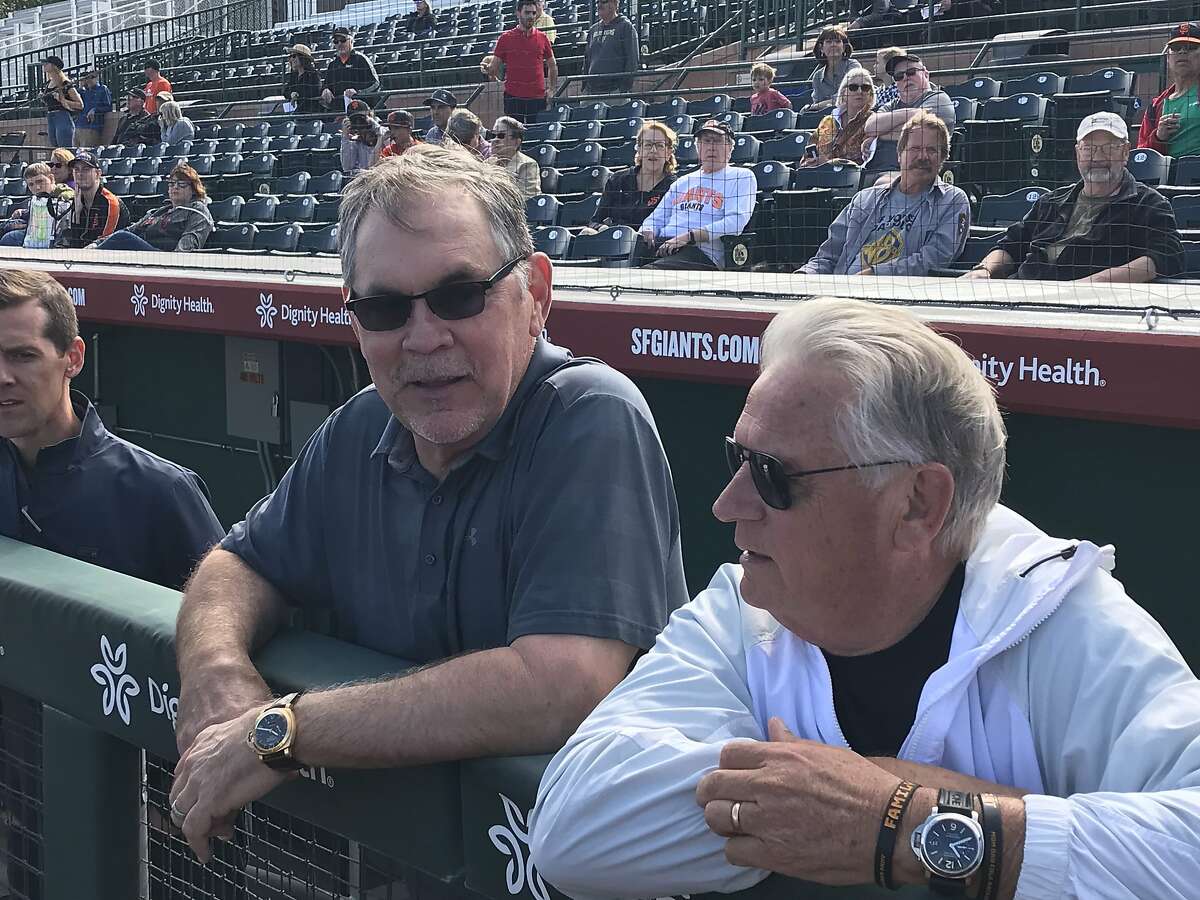 Former manager Bruce Bochy chats with broadcaster Duane Kuiper as they watch Friday's workout at Scottsdale Stadium.