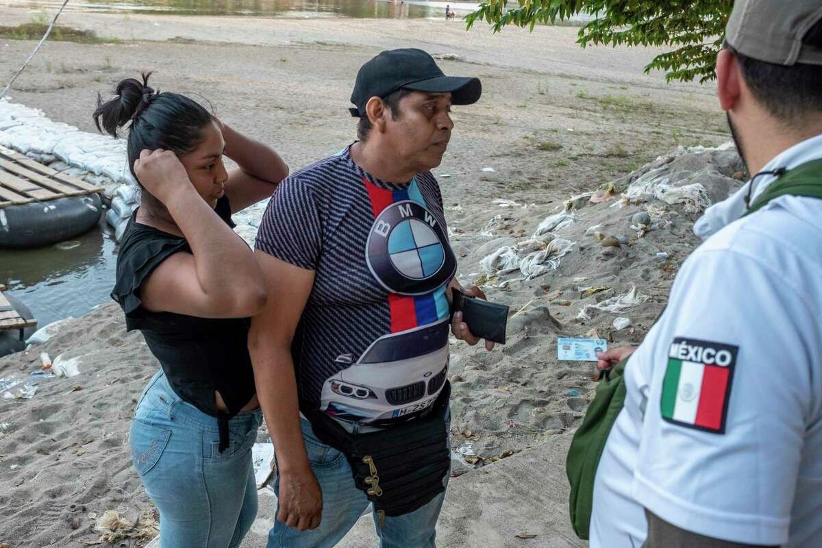 People crossing the Suchiate River on truck tire rafts between Tecún Umán, Guatemala and Ciudad Hidalgo, Mexico, are checked for identity papers, passports and permission papers by Mexican immigration officers stationed on a levee above the banks of the river.