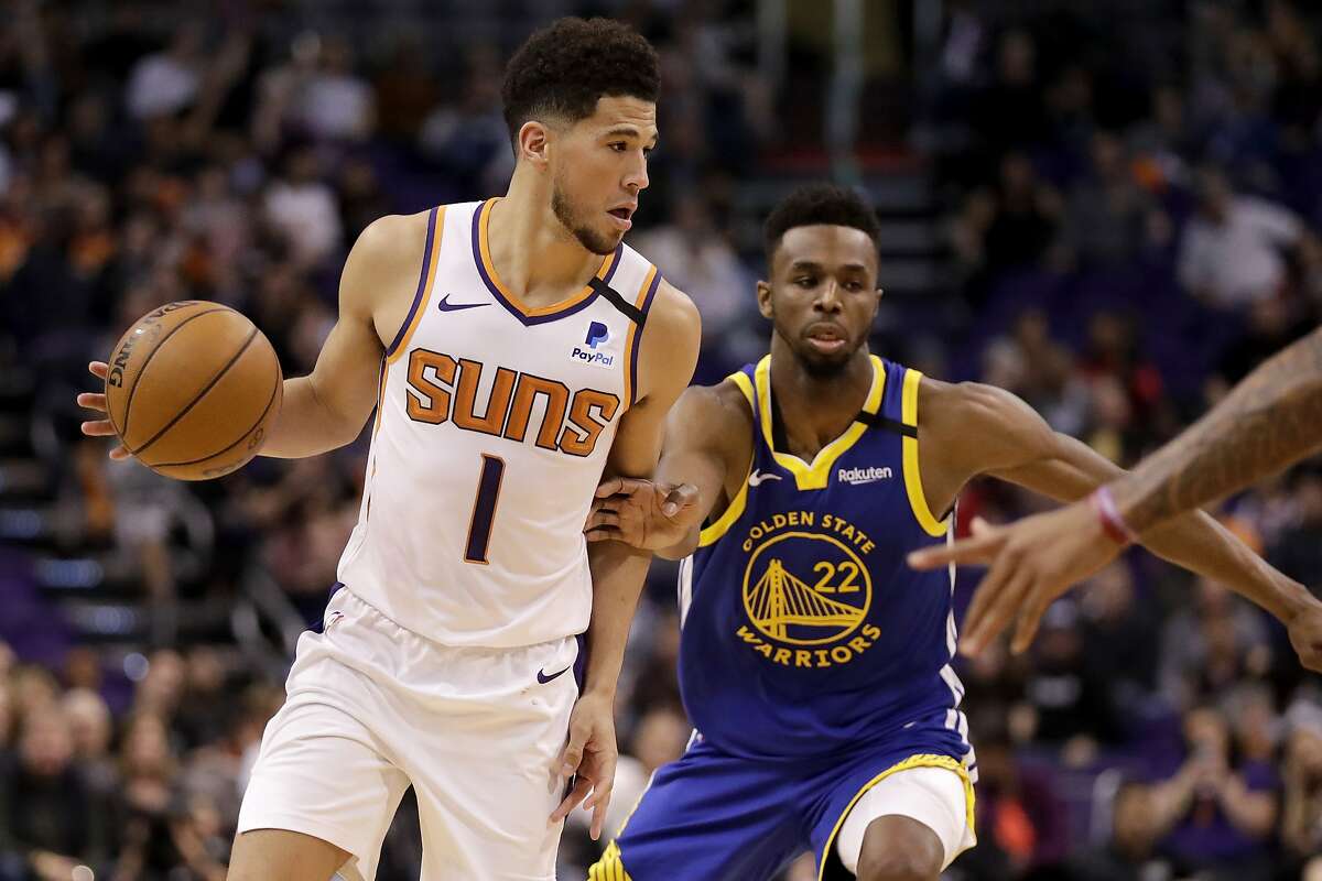 Phoenix Suns guard Devin Booker (1) looks to pass as Golden State Warriors guard Andrew Wiggins (22) defends during the second half of an NBA basketball game, Wednesday, Feb. 12, 2020, in Phoenix. (AP Photo/Matt York)