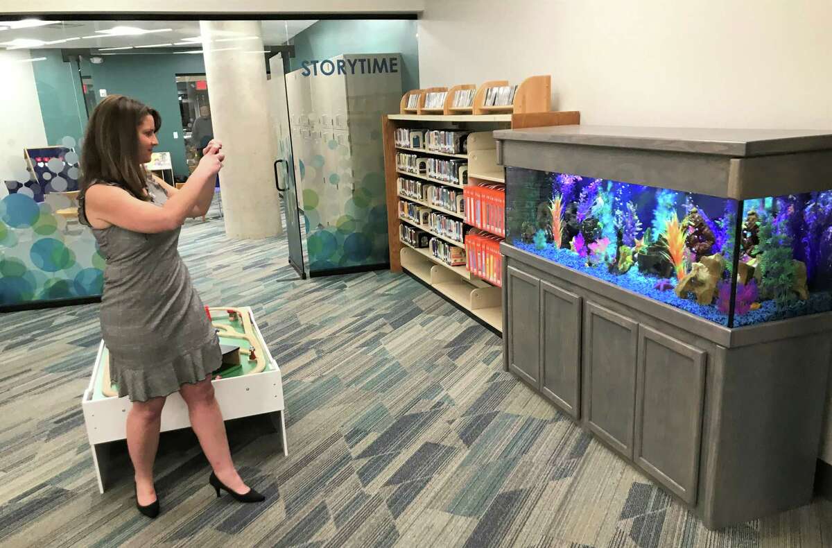 State Rep. Christie Carpino takes a photo of a new fish tank that has been installed in the Children's Library in Cromwell and is already a source of fascination for young patrons.