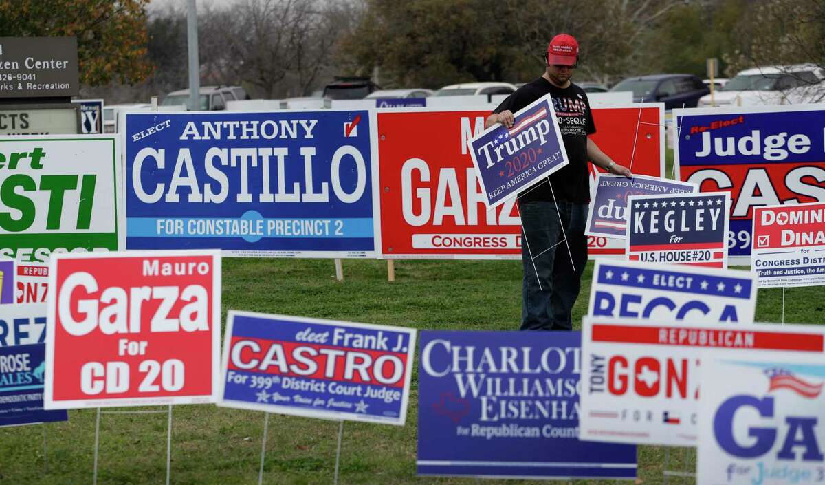 Joe Michael places election signs near an early voting site in San Antonio, Tuesday, Feb. 18, 2020. Early primary voting for began Tuesday for Texas and Arkansas ahead of Super Tuesday. (AP Photo/Eric Gay)