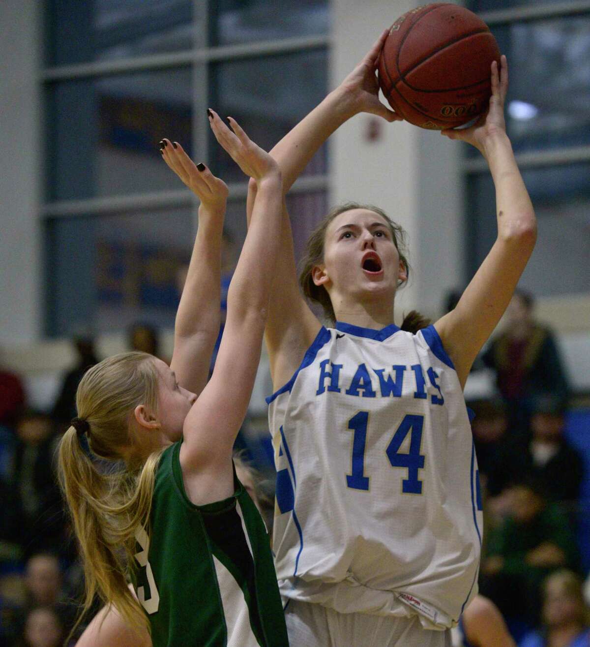 Newtown’s Juliette Cryder (14) goes up with the ball over New Milford’s Anna Holcomb (3) in the girls’ SWC basketball tournament quarterfinal game on Friday night at Newtown High School.