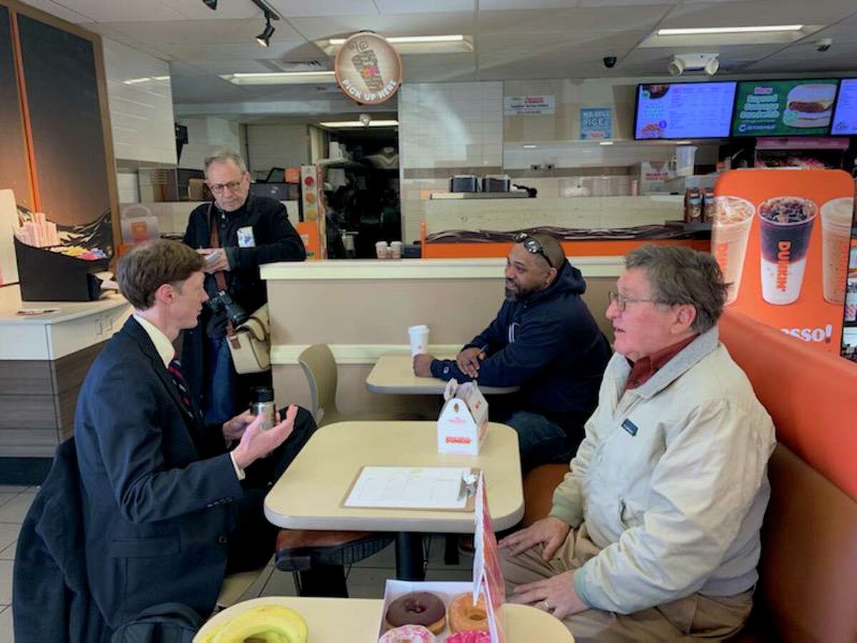 New Haven Mayor Justin Elicker, left, sits with area residents during a gathering over coffee at a Dunkin’ shop in New Haven to discuss issues in the city.