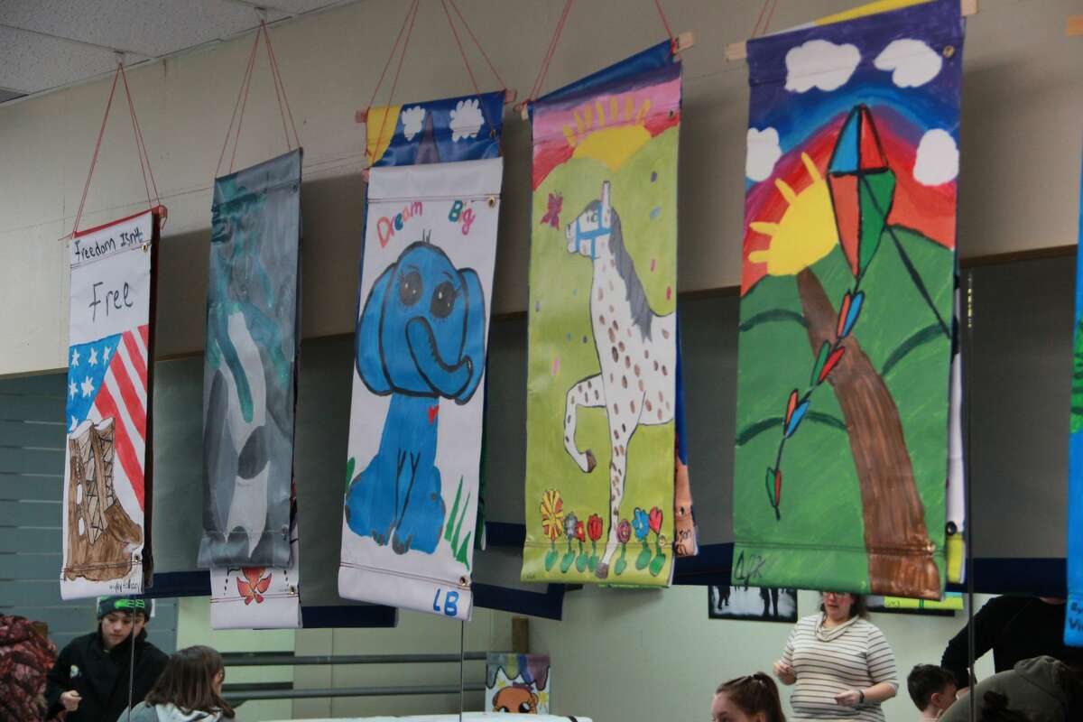 Above, banners hang from the ceiling in 2020. Festival of Banners returns for 2022. Residents of all ages may paint banners which will be displayed on light posts around Big Rapids. One side of the banner shows the business sponsors, while the other side displays artwork done by kids, teens and adults.