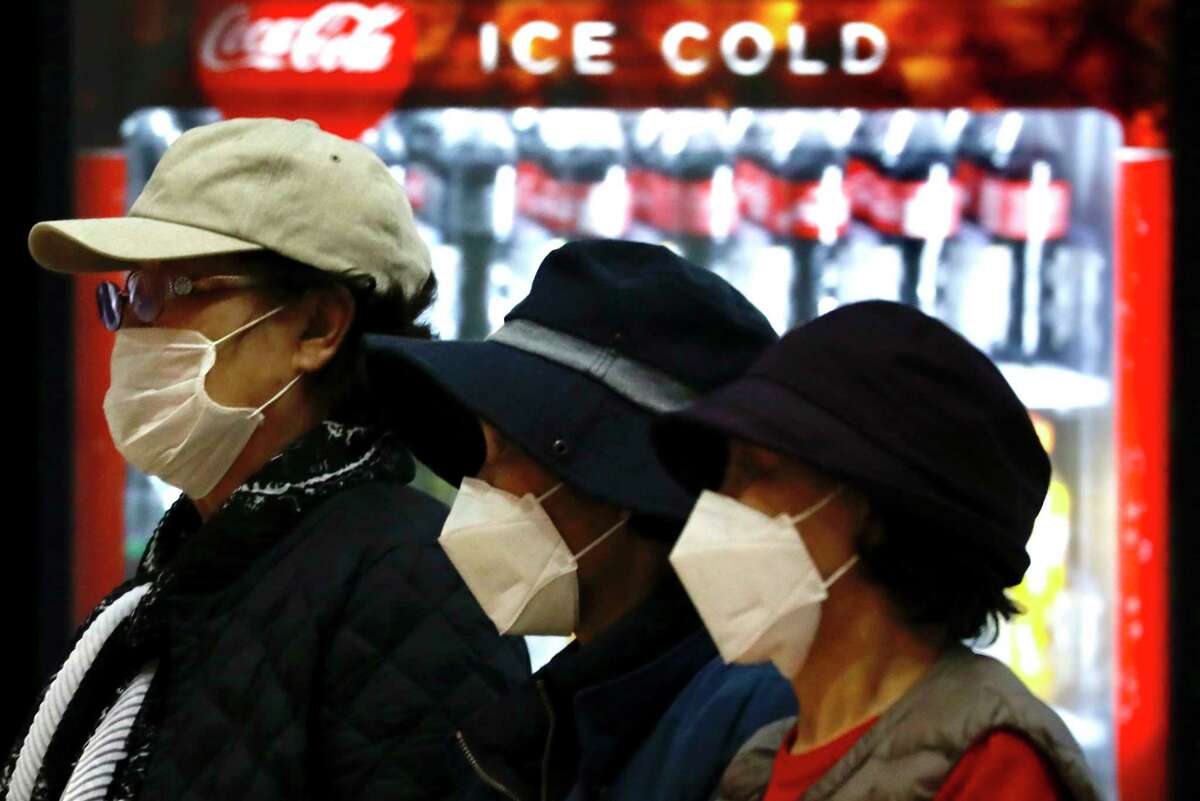 Tourists from Korea wearing protective masks walk with their belongings while waiting for a flight back to South Korea at the Ben Gurion airport near Tel Aviv, Israel, Monday, Feb. 24, 2020.  On Thursday, Israel Science and Technology Minister Ofir Akunis said researchers were developing a vaccine for COVID-19 that could be ready in 90 days.