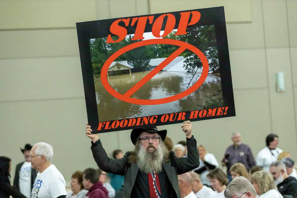 Frantisek Uncajtyk holds an image of his flooded from Hurricane Harvey during a San Jacinto River Authority meeting at the Lone Star Convention Center, Thursday, Feb. 20, 2020, in Conroe