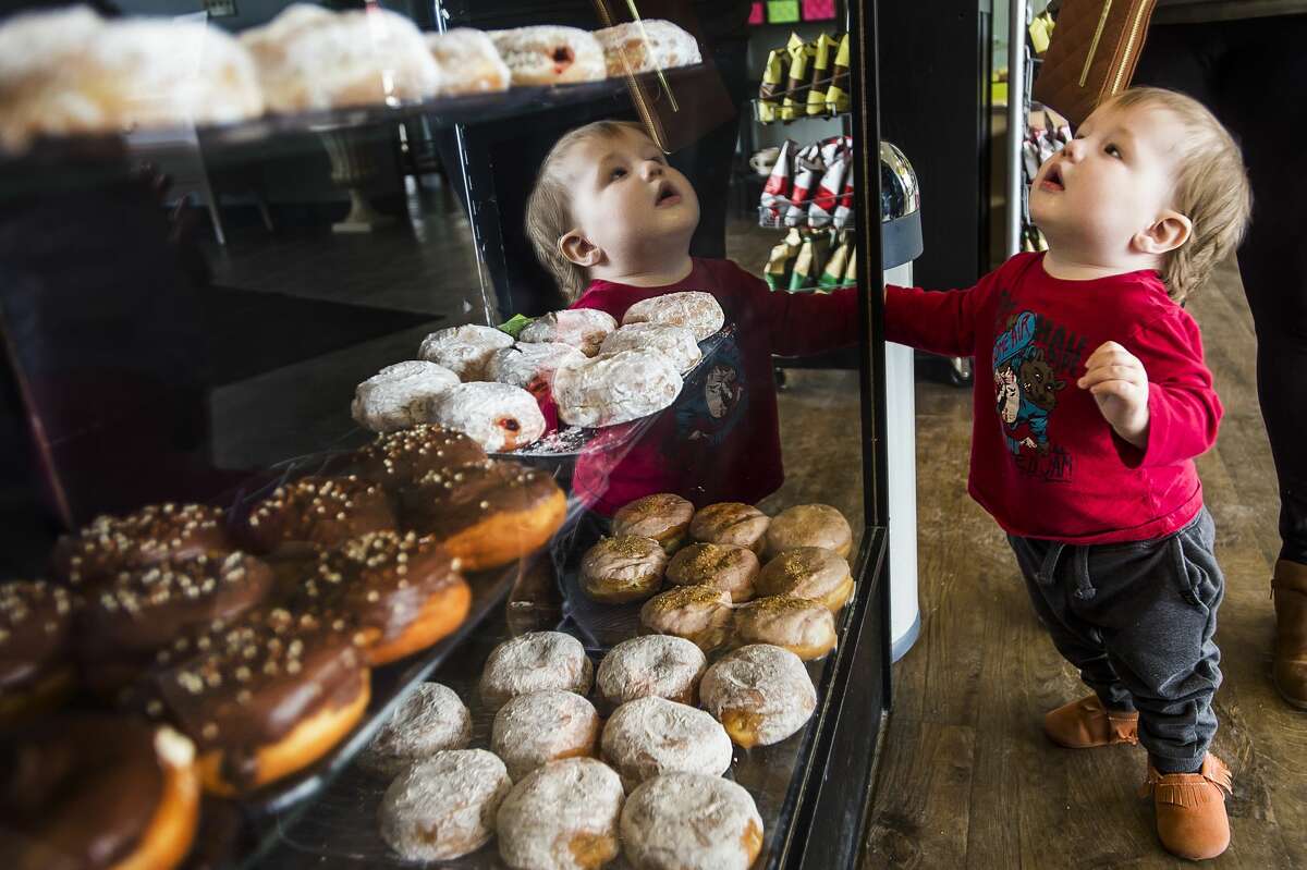 Micah Andrews, 11 months, peers through the glass at a display of paczkis at The Gourmet Cupcake Shoppe on Monday, Feb. 24, 2020 in Midland. (Katy Kildee/kkildee@mdn.net)