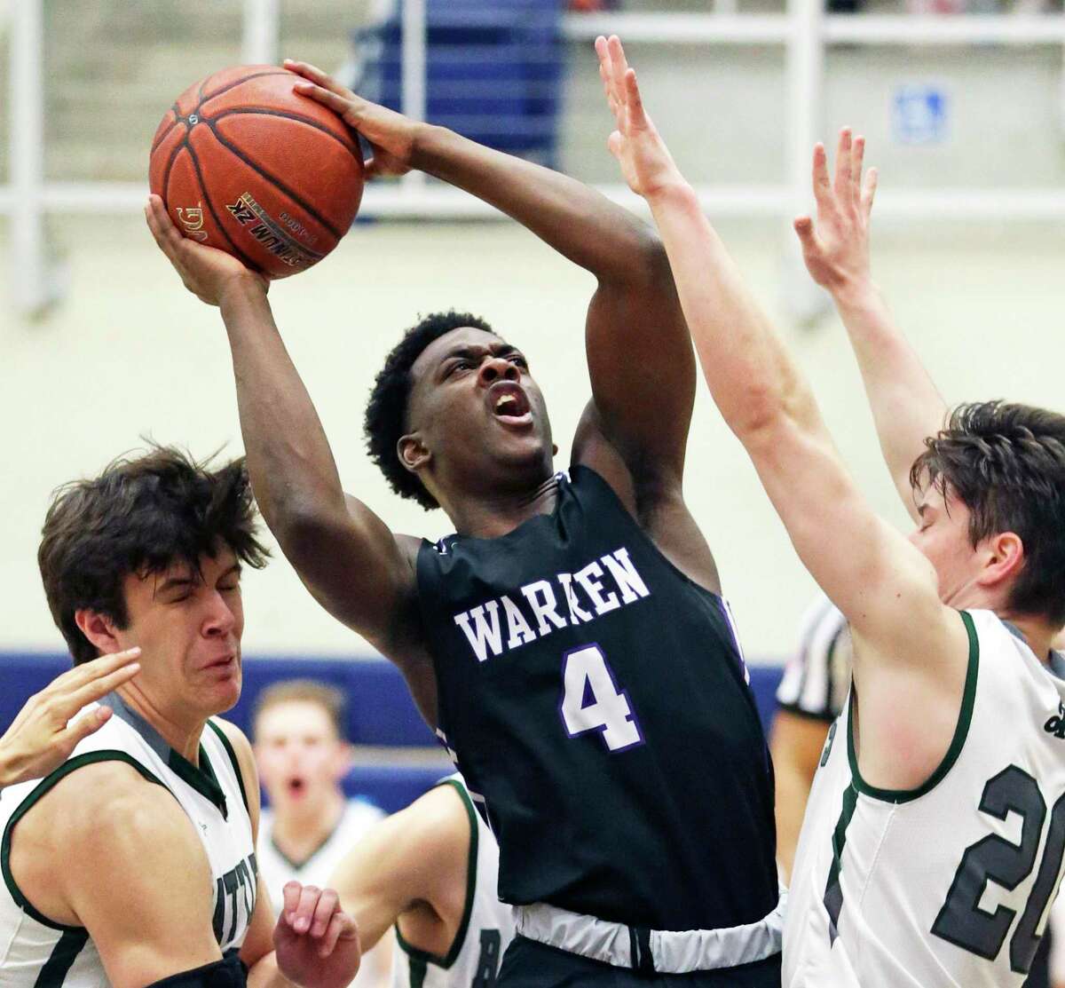 Zane Elmore battles in the lane to put up a shot against Will Carsten, left, and Zach Lee as Warren plays Reagan in boys basketball playoff action at Taylor Field House on Feb. 24, 2020.