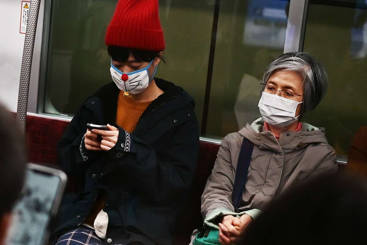 People wearing face masks travel on a train in Tokyo on February 25, 2020. - Japan has more than 150 cases of the COVID-19 coronavirus and five have died. Four of those deaths were passengers who had been on the cruise ship Diamond Princess, quarantined off in Yokohama, where the number of infections is over 690. (Photo by CHARLY TRIBALLEAU / AFP) (Photo by CHARLY TRIBALLEAU/AFP via Getty Images)