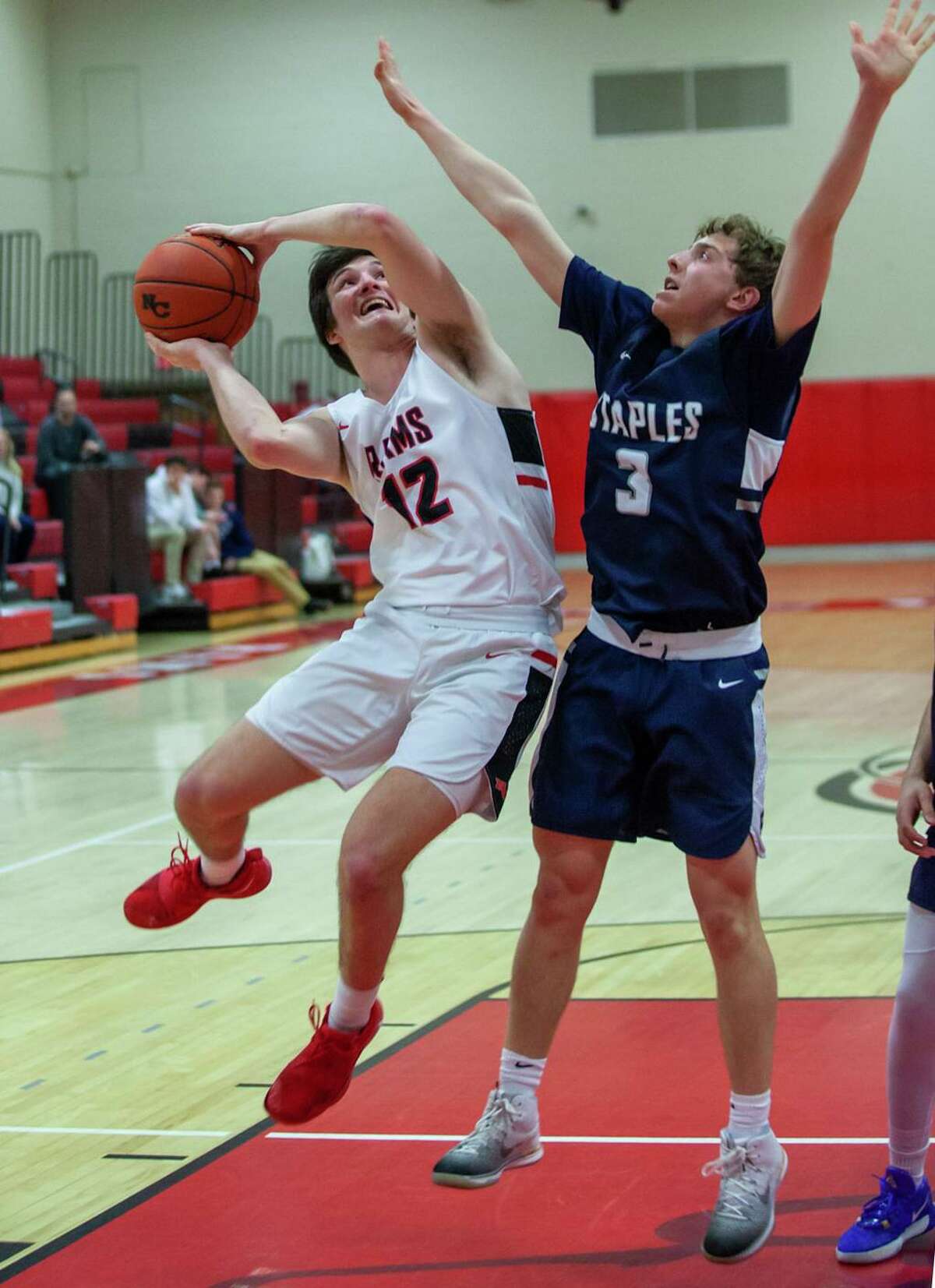 New Canaan's Christian Sweeney (12) goes up for a shot, while Staples' Derek Sale (3) defends during a boys basketball game at New Canaan High School on Monday, Feb. 24, 2020.