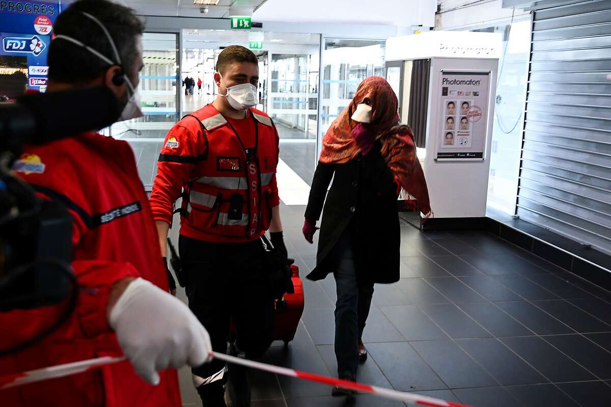A woman wearing a protective facemask is evacuated from the security zone where a bus comming from Milan is blocked at the train and bus station Lyon Perrache, due to suspected COVID-19 the novel coronavirus on board, in Lyon, on February 24, 2020. (Photo by JEAN-PHILIPPE KSIAZEK / AFP) (Photo by JEAN-PHILIPPE KSIAZEK/AFP via Getty Images)