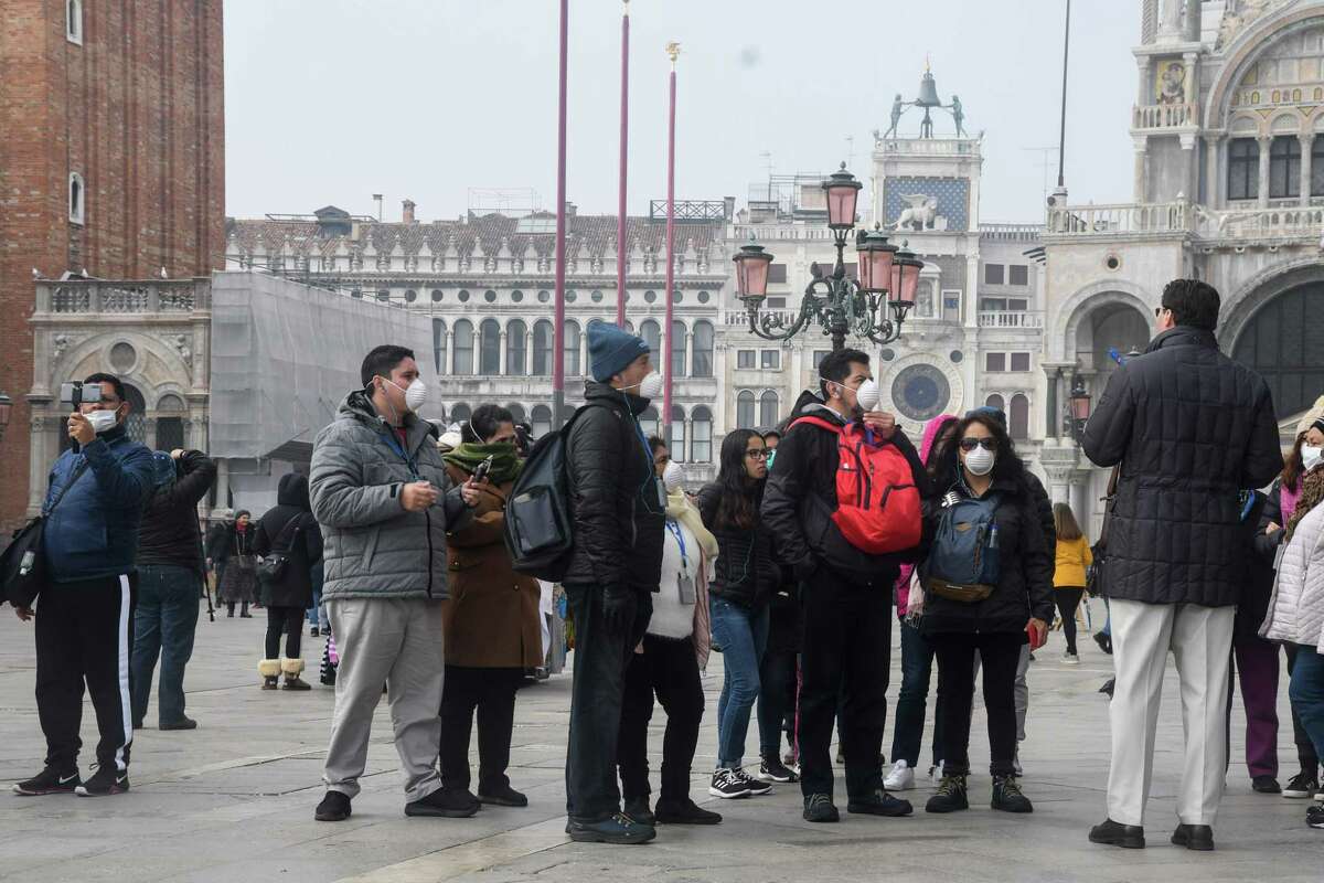 Tourists wearing protective masks visit Venice on Feb. 25, 2020, during the usual period of the Carnival festivities which have been cancelled following an outbreak of the COVID-19 novel coronavirus in northern Italy.