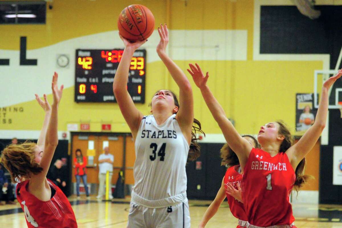 Staples' Arianna Gerig (34) goes up for a shot between Greenwich's Ciara Munnelly (4), left, and Ava Sollenne (1) during FCIAC Girls' Basketball Quarterfinals action in Trumbull, Conn., on Tuesday Feb. 25, 2020.