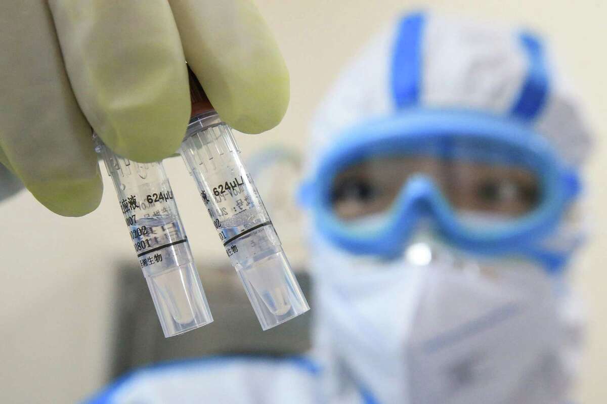 This photo taken on February 19, 2020 shows a laboratory technician holding samples of virus at a laboratory in Hengyang in China's central Henan province. - The death toll from the COVID-19 coronavirus epidemic jumped to 2,112 in China on February 20 after 108 more people died in Hubei province, the hard-hit epicentre of the outbreak.