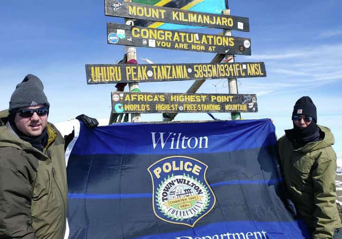 Lt. David hartman and Lt. Robert Kluk display a Wilton Police Department flag at the summit of Mount Kilimanjaro in Africa. They scaled the mountain as a fundraiser for Special Olympics.