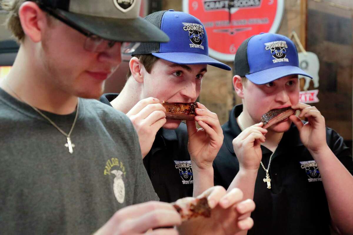 Katy students (from left) Austin Flynn, Kyle Foster and Walker Mills, from James E. Taylor High School’s FFA barbecue team, known as the Teenage Mutant Ninja Cookers, sample smoked ribs prepared by pitmaster and mentor Brett Jackson at his restaurant, Brett’s Barbecue Shop.