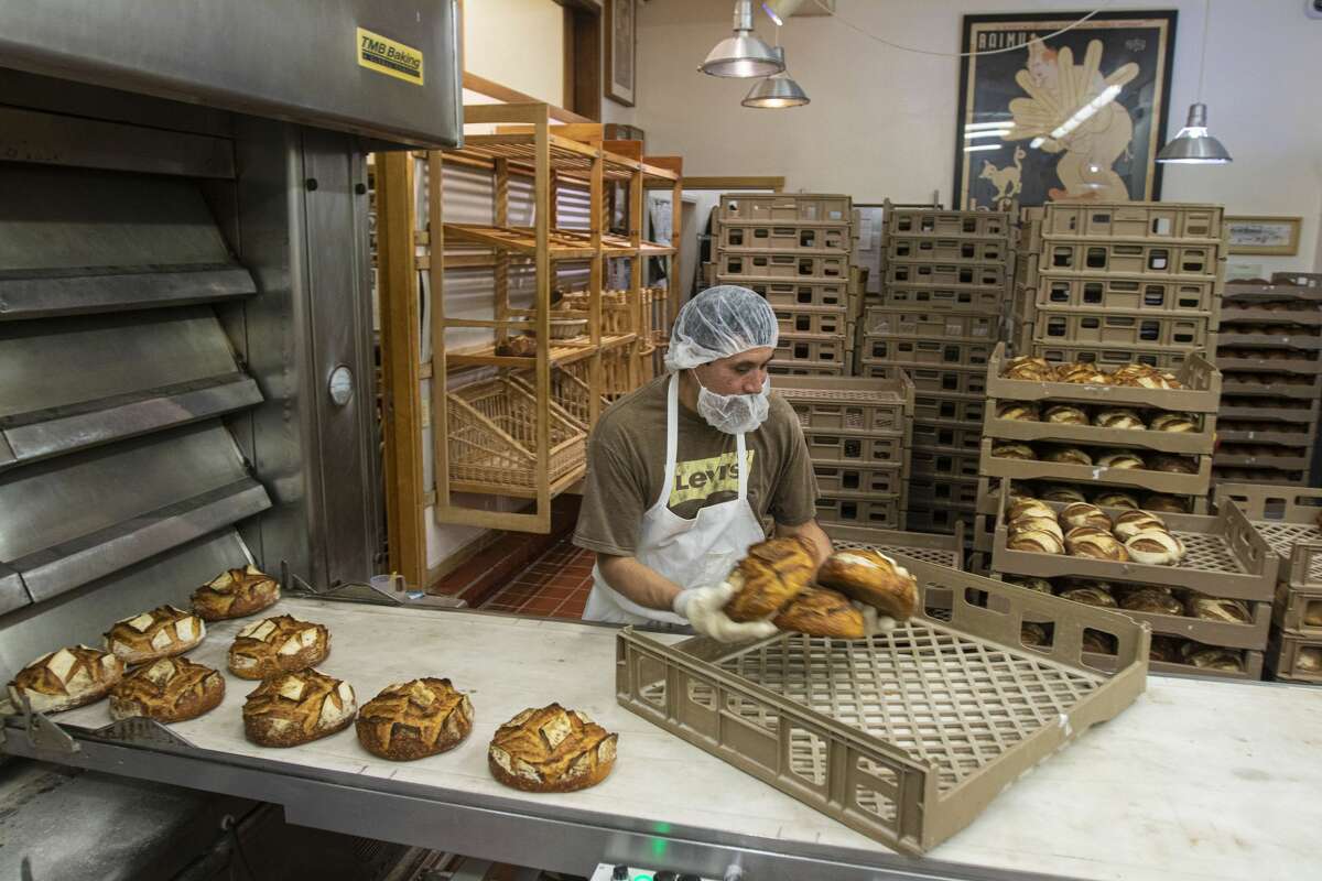 Armando Castillo takes bread out of the oven during an evening shift at Acme Bread Company in Berkeley, Calif., Tuesday, Feb. 25, 2020.