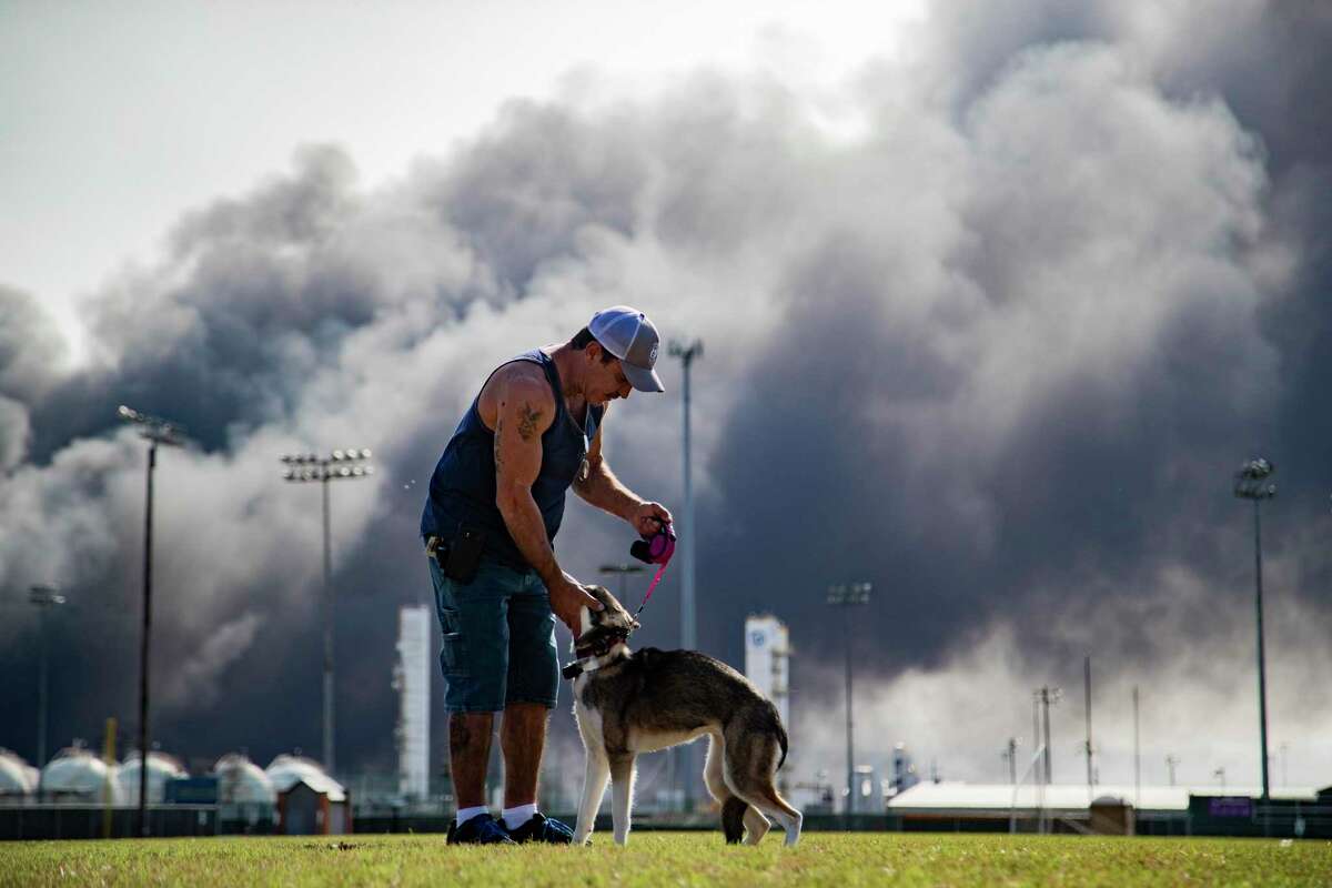 Ray Moore trains his dog Aries with a cloud of smoke on the background from the TPC Group Port Neches Operations explosion on Wednesday, Nov. 27, 2019, in Port Neches.