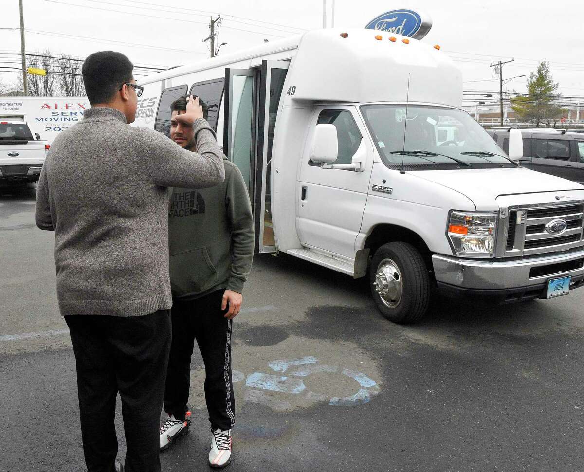 Luis Lavoura of Stamford receives ashes from Tyler Tarver, an Ambassador of Faith for St. Matthew's Church, during stop in Stamford, Conn. on Feb. 26, 2020 for the churches annual Ashes on the Move. As part of an out reach for the church, the church parish sends out the St. Matthew Bus onto the streets to offer people ashes on Ash Wednesday. It's about meeting people where they are , telling them about our great Catholic Church and to invite them in. Lavoura, a student at the University of St. Joseph, Connecticut, who recently moved to Stamford, went to the internet to find a local church offering Ashes and saw a posting about St. Matthews Ashes on the Move. He was one of a dozen people to receive ashes at the Stamford stopped outside of the Stamford Lincoln Ford dealership on McGee Avenue, one of twelve stops throughout Fairfield County.