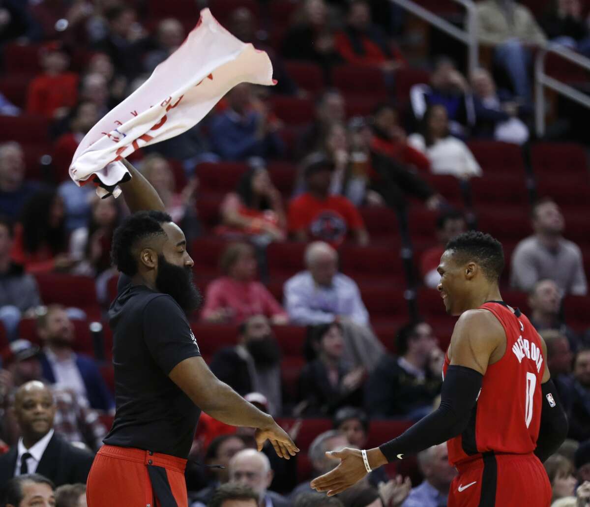 Houston Rockets guard James Harden, left, waves a towel as he slaps hands with guard Russell Westbrook (0) as he comes off the court during the second half of an NBA basketball game against the Memphis Grizzlies on Wednesday, Feb. 26, 2020, at Toyota Center in Houston.
