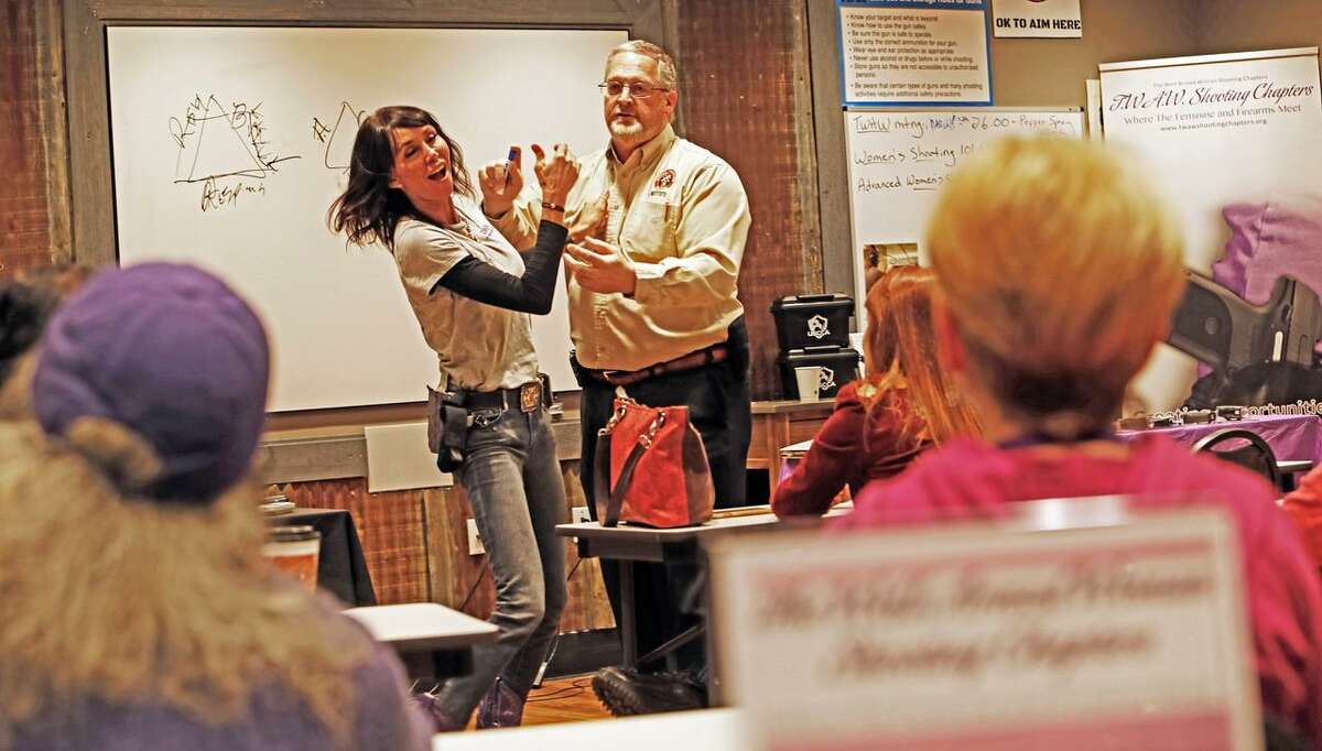 Holding a dummy canister, Ken Lewis demonstrates how to repel an attacker with pepper spray while Kari Grayson, founder of the San Antonio chapter of The Well Armed Woman, responds during a clinic at the monthly meeting of the club that focuses on firearms and self-defense.