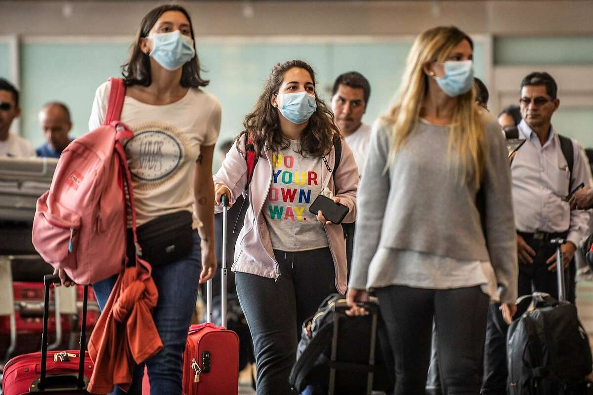 Passengers walk while wearing protective masks, as a preventive measure regarding the COVID-19 virus, at Jorge Chavez International Airport, in Lima on February 27, 2020. - So far, Peru has no record of the COVID-19 virus cases. (Photo by Ernesto BENAVIDES / AFP) (Photo by ERNESTO BENAVIDES/AFP via Getty Images)