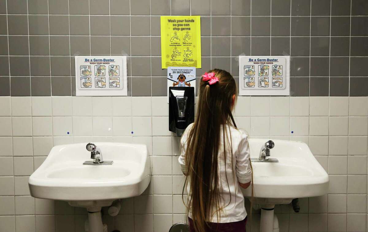 A first-grade student at Oak Crest Elementary in East Central ISD shows how she washes her hands in a bathroom Thursday, Feb. 27, 2020. The school has posted signs in restrooms and one in the main hallway to remind students about hygiene and proper hand washing and the district has sent letters to parents about precautionary measures to guard against coronavirus (COVID-19).