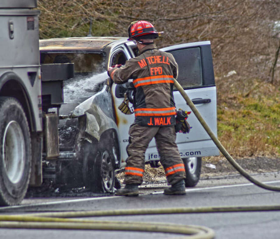 A firefighter from Mitchel Fire Department extinguishes any remaining flames coming from a pick-up truck that was on fire blocking the I-255 northbound exit ramp to New Poag Road Thursday afternoon. Photo: Tyler Pletsch | The Intelligencer