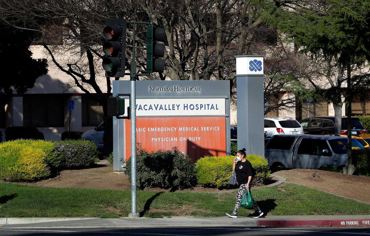 A woman, who declined comment, walks by Vacavalley Hospital after leaving the building where a female patient went for treatment of flu-like symptoms and was not tested for Covid-19 as she didn’t fit the CDC’s criteria in Vacaville, Calif., on Thursday, February 27, 2020. She was eventually tested and found to be positive before being transferred to UC Davis Medical Center in Sacramento.
