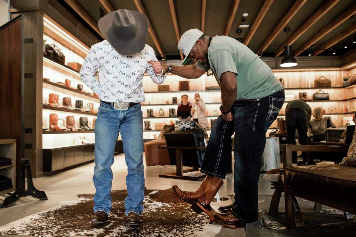 Josh McPherson, left, helps Ricky Williams take off a pair of boots as he shops for a new pair at Tecovas in Rice Village on Tuesday, Feb. 25, 2020 in Houston. With the Houston Livestock Show and Rodeo fast approaching, Houstonians are gearing up for the annual Go Texan Day. You don't have to be born Texan. Anyone can go Texan. It's not about history; it's about attitude and a willingness to play along and belong to the place.