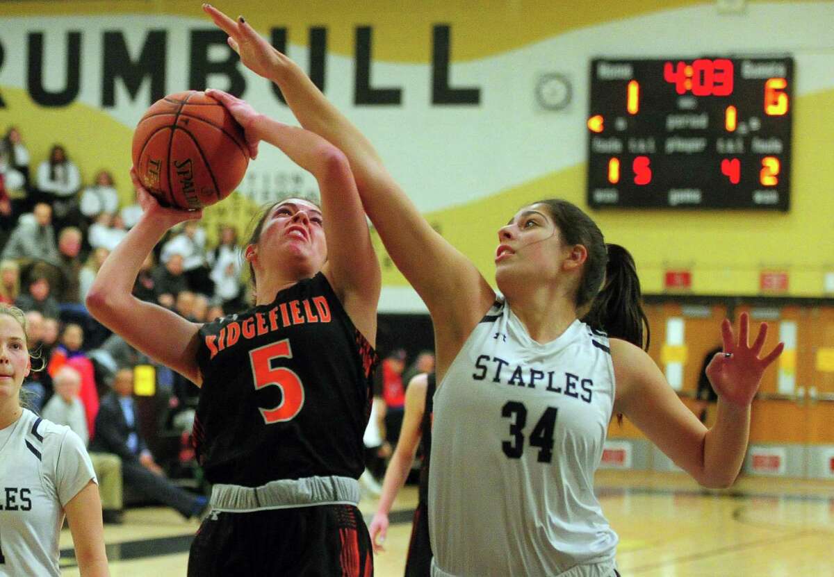 Ridgefield’s Cara Sheafe (5) looks to score as Staples’ Arianna Gerig (34) defends during FCIAC Girls’ Basketball Championship in Trumbull on Thursday. For more information, go to newstimes.com/sports.