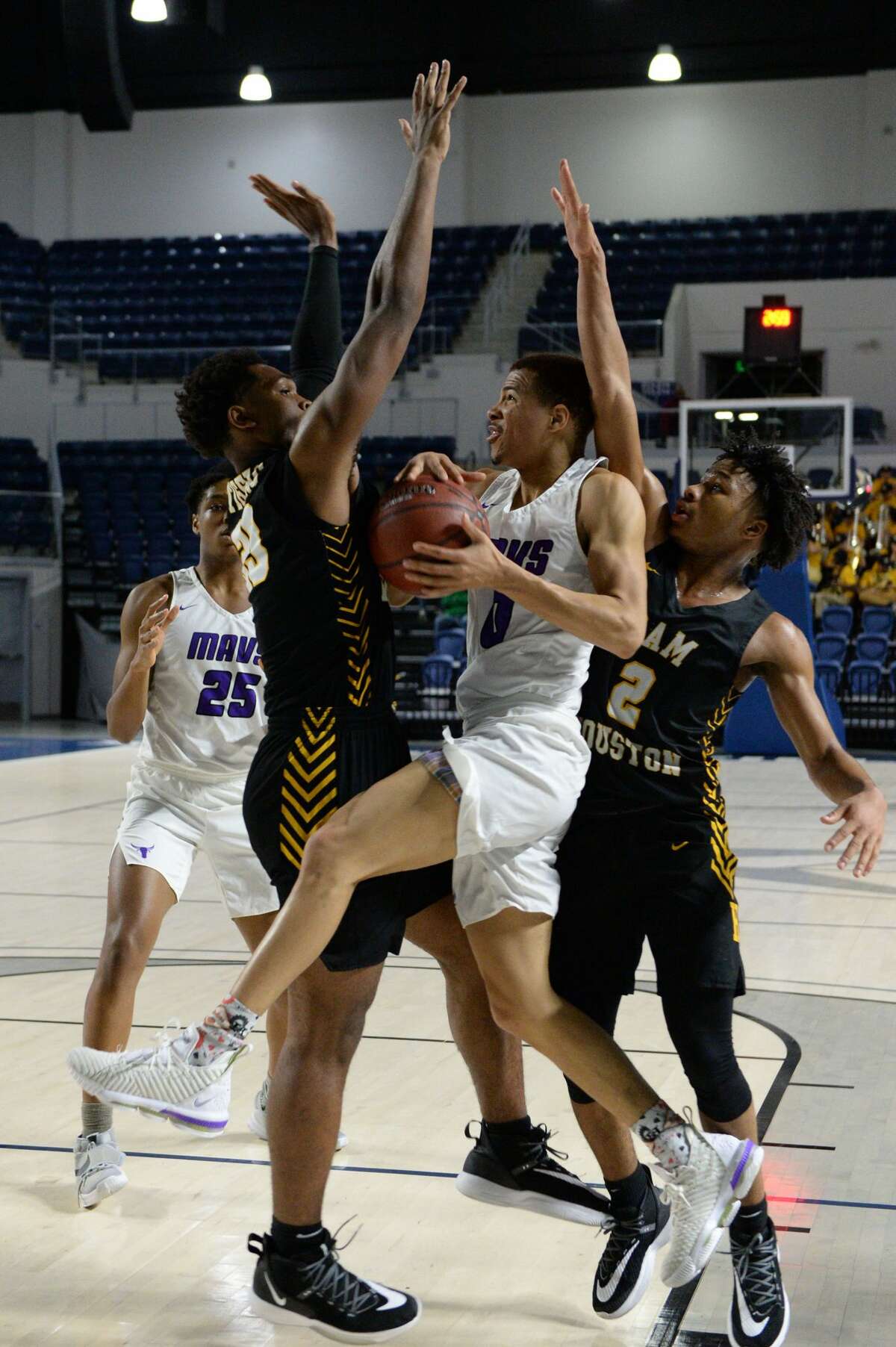 Westley Sellers (0) of Morton Ranch drives to the basket between a pair of Tiger defenders during the fourth quarter of the Boys 6A Region III Area play-off game between the Morton Ranch Mavericks and the Sam Houston Tigers on Thursday, February 27, 2020 at Delmar Fieldhouse, Houston, TX.