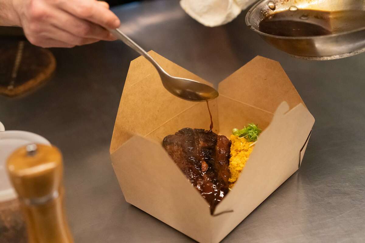 Prubechu chef Manfred Wrembel drizzles sauce over their Guam style BBQ pork ribs made to go on Friday, Feb. 28, 2020, in San Francisco, Calif.