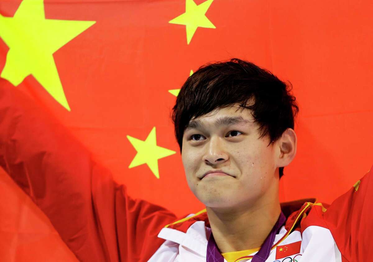 FILE - In this Saturday, Aug. 4, 2012 file photo, China's Sun Yang holds his national flag after winning the gold medal in the men's 1500-meter freestyle swimming final at the Aquatics Centre in the Olympic Park during the 2012 Summer Olympics in London. Chinese swimmer Sun Yang has been banned for eight years for breaking anti-doping rules and will miss the 2020 Tokyo Olympics. (AP Photo/Lee Jin-man, File)