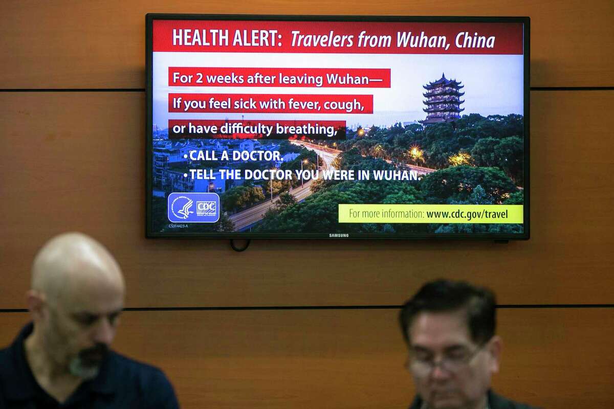 A sign advising travelers from Wuhan, China, to be on the lookout for signs of COVID-19 hangs above the Allegiant Air ticket counter at the San Antonio International Airport on Feb. 28, 2020.