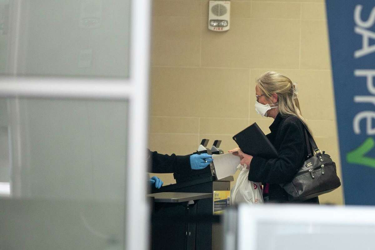 A woman wears a surgical mask as she makes her way through the TSA security line at San Antonio International Airport. Masks have become more common as a way of preventing the spread of colds and flu, nevermind the new coronavirus.