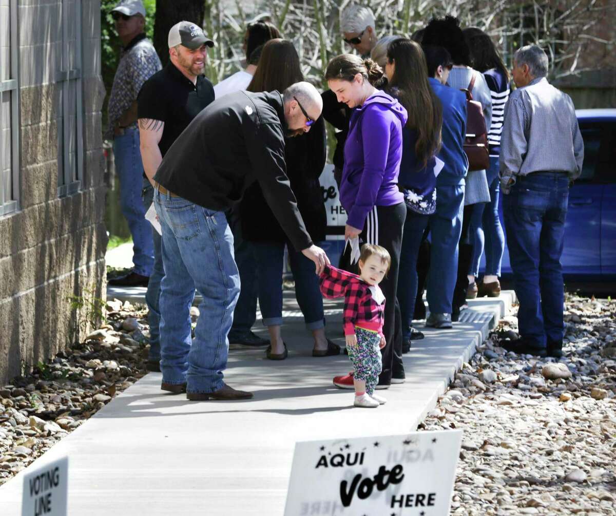 Joseph Mahan grabs the hood of Charlotte, his daughter, as he and his wife Carrie Mahan stand in line to vote at Brook Hollow Public Library on the last day of early voting.