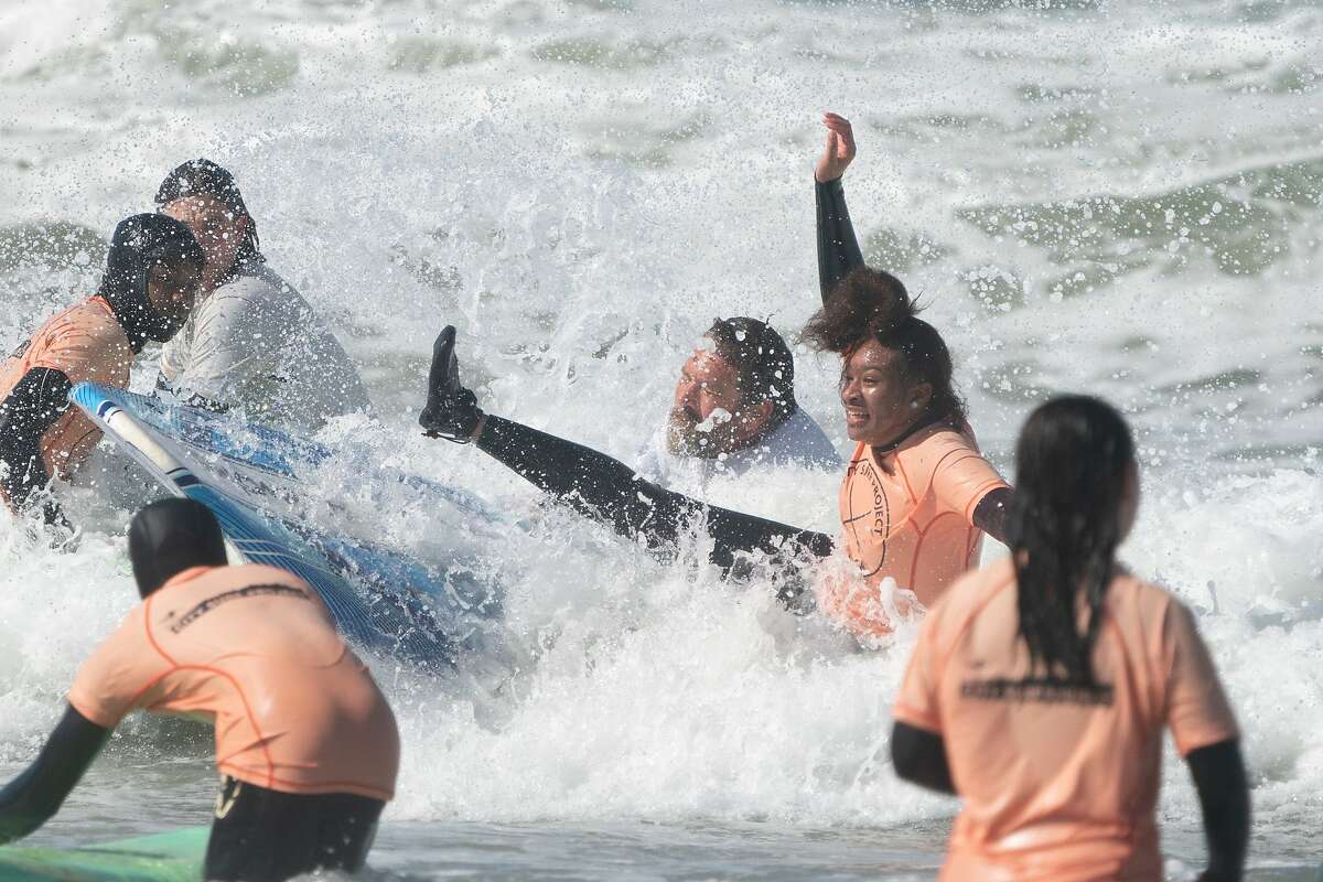 Ereese Beverly, 14, falls as she learns to surf with the City Surf Project and Presidential candidate Tulsi Gabbard (out of photo) at Linda Mar Beach on Saturday, Feb. 29, 2020, in Pacifica , Calif.