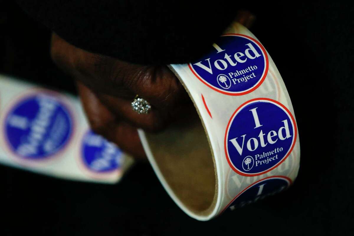 A worker holds stickers at a polling place for the South Carolina primary election, Saturday, Feb. 29, 2020, in Columbia, S.C. (AP Photo/Matt Rourke)