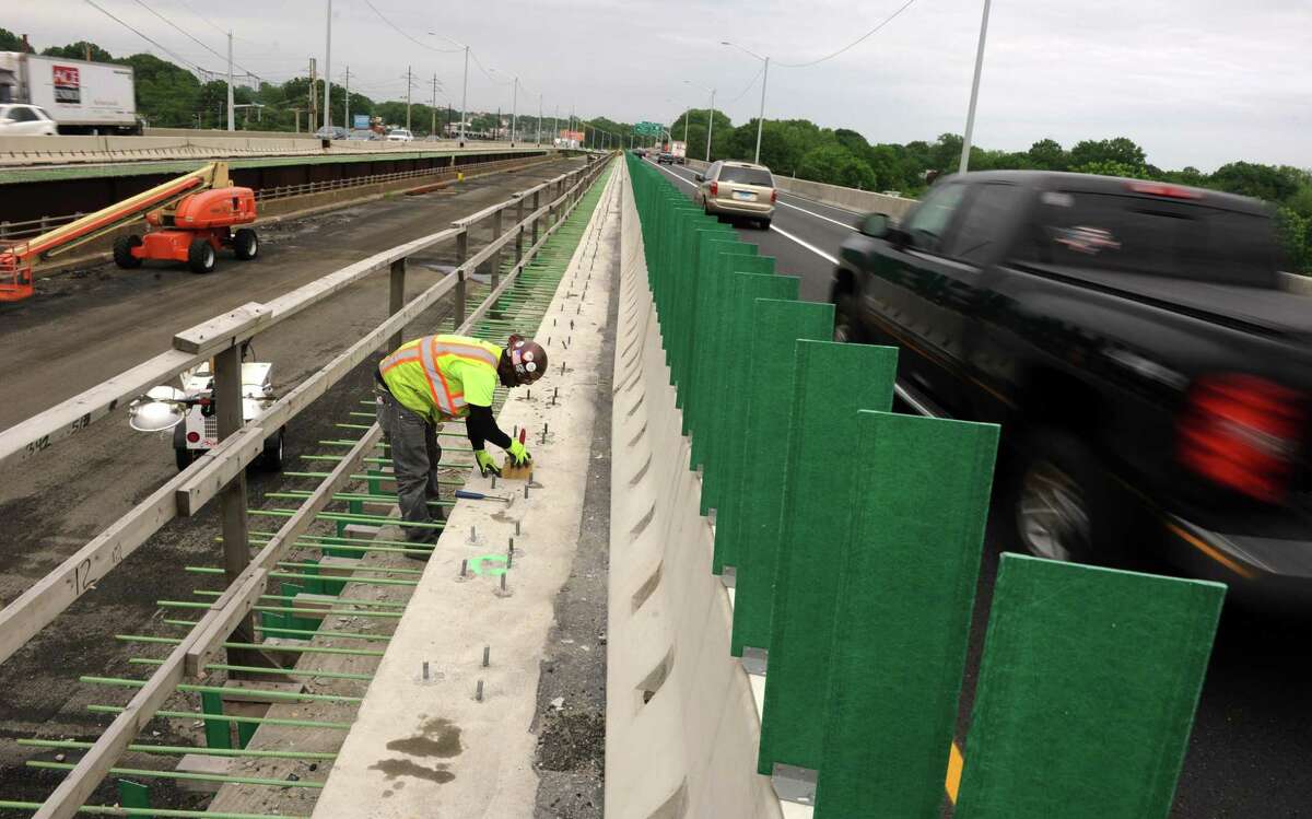 Edward Murphy, with Walsh Construction, levels off concrete as cars and trucks whiz past on I-95 while working on the Moses Wheeler Bridge between Milford and Stratford.